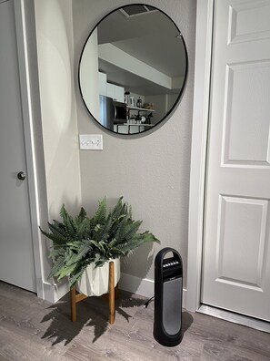 A hallway with a white door, a round mirror, a potted fern, and a black speaker. - Wine Country King Suite,  Full Kitchen, Laundry, Walk to WWU, 10 Min to WW (College Place)