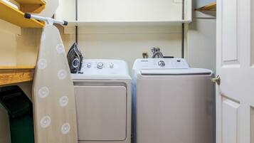 A laundry area with two washing machines and a drying rack.