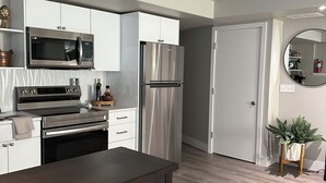Una cocina moderna con armarios blancos, electrodomésticos de acero inoxidable y una mesa de comedor de madera.