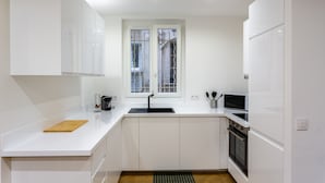 Eine moderne Küche mit weißen Schränken, einem schwarzen Spülbecken und einem Fenster mit Gitterstäben.