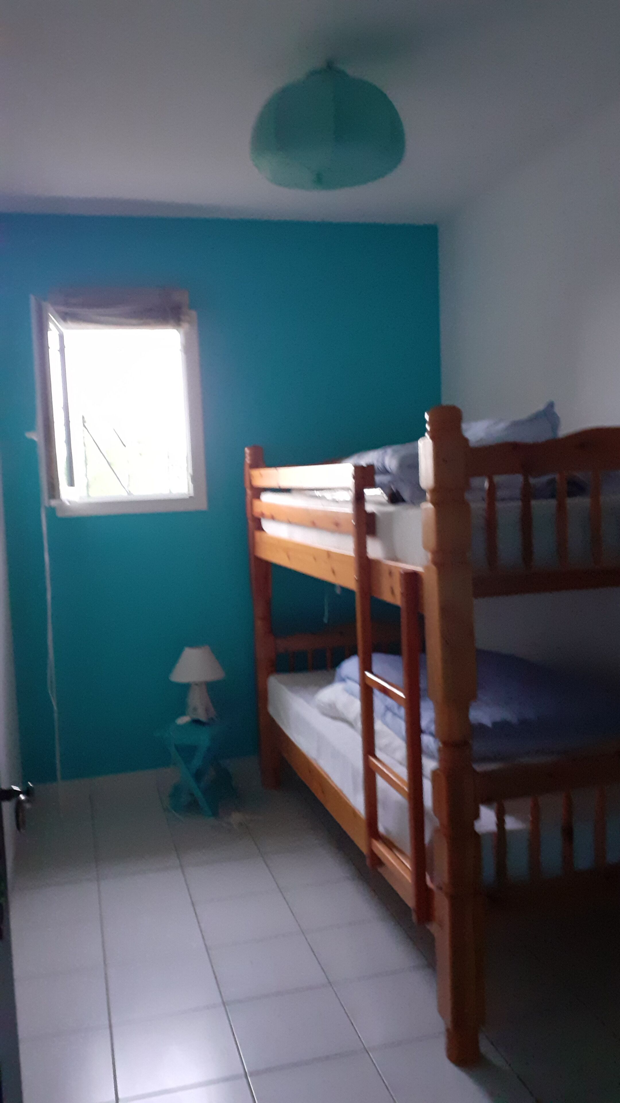 Quarto com beliche, janela, luminária e luminária de teto.