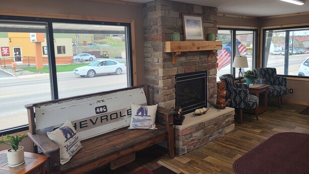 A cozy room with a stone fireplace, a bench, and a view of the street outside. - The B&B Motel (Lewistown)