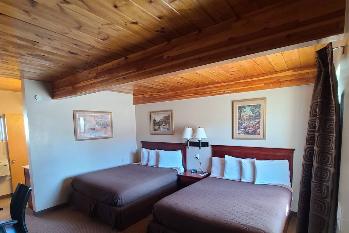 A room with two beds, a desk, and a chair.