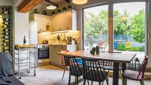 Un salon confortable avec un canapé, une table à manger et des chaises, une cuisine dotée d’une grande fenêtre et un meuble à vin.