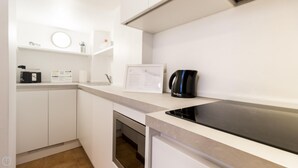 A modern kitchen with white cabinetry, a black countertop, a coffee maker, and a framed menu on the wall. - Italianway Comfort - San Maurilio 20 B (Milan)