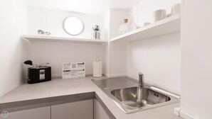 A modern kitchen with a stainless steel sink, a round mirror, and a white countertop. - Italianway Comfort - San Maurilio 20 B (Milan)