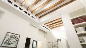 Ein modernes Interieur mit freiliegenden Holzbalken, weißen Wänden und einem Oberlicht.