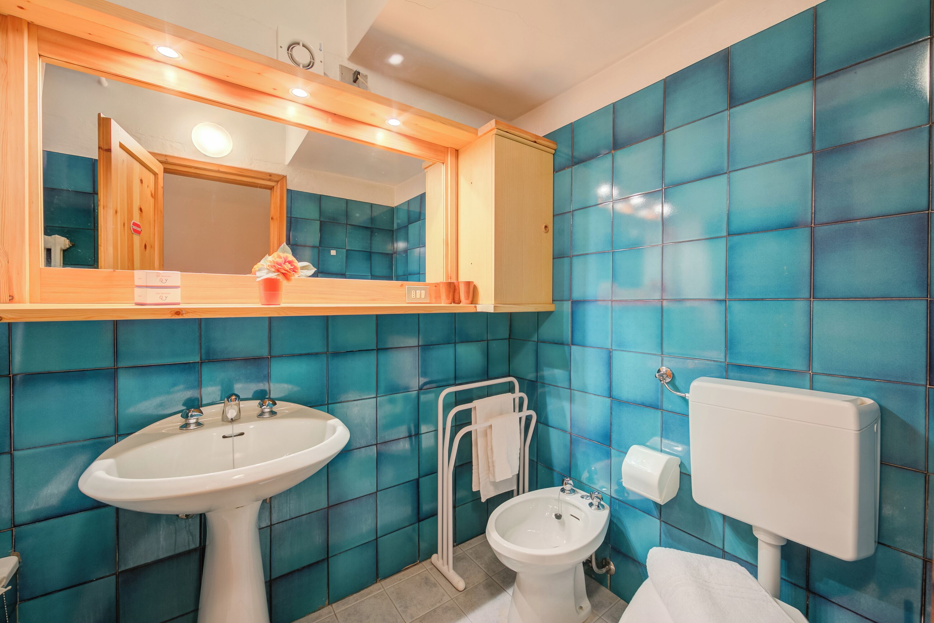 A bathroom with a sink, bidet, toilet, and a mirror with a wooden frame.