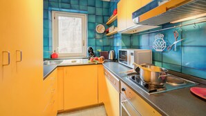 Keittiössä on turkoosinsiniset ja keltaiset laatat, ruostumattomasta teräksestä valmistetut kodinkoneet ja ikkuna.