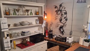 A kitchen with a wooden table, white cabinets, and various kitchen items.