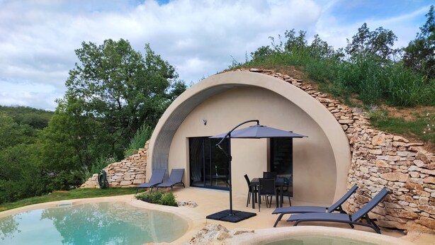 Area piscina moderna all'aperto con lettini e vasca idromassaggio, circondata da muri in pietra e vegetazione.