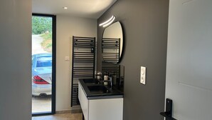 Un bagno moderno con lavabo, specchio e zona doccia.