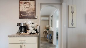 Uma cozinha com cafeteira, um letreiro decorativo e uma obra de arte com garfo na parede.