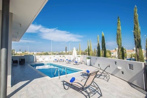 A rooftop pool area with lounge chairs and a view of the sea. - Villa Polymnia Protaras 1 (Paralimni)