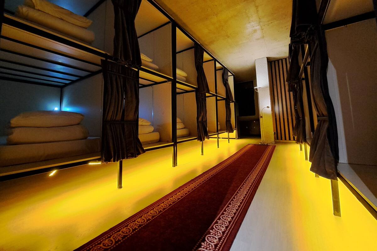 A hotel corridor with bunk beds, a red carpet, and a modern design.