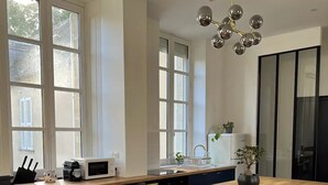 Une cuisine moderne dotée d’un grand îlot central, de tabourets de bar et d’un luminaire suspendu.