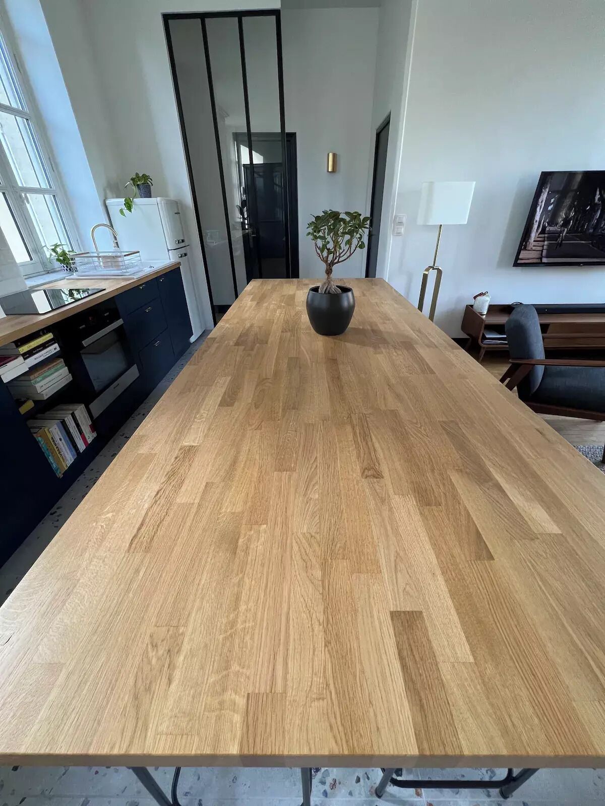 Une cuisine moderne avec une table en bois, une plante en pot et une bibliothèque.