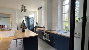 Une cuisine moderne dotée d’un îlot central, d’appareils électroménagers intégrés et de grandes fenêtres.