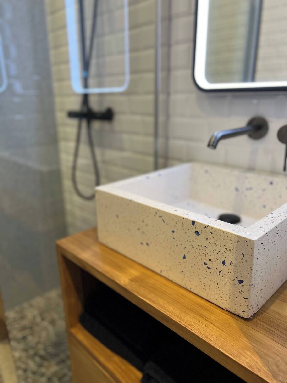 Ein Badezimmer mit einem rechteckigen Waschbecken, einem Holz-Waschtisch und einem Spiegel darüber.
