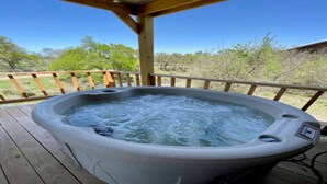 Een hottub op een houten terras, met vrij uitzicht op het omliggende landschap.