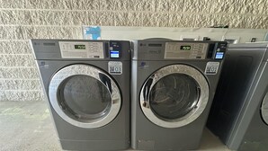 Dos lavadoras comerciales LG con pantallas digitales y códigos QR para el pago.