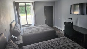 Habitación de hotel con dos camas, un televisor y una puerta corredera al exterior.