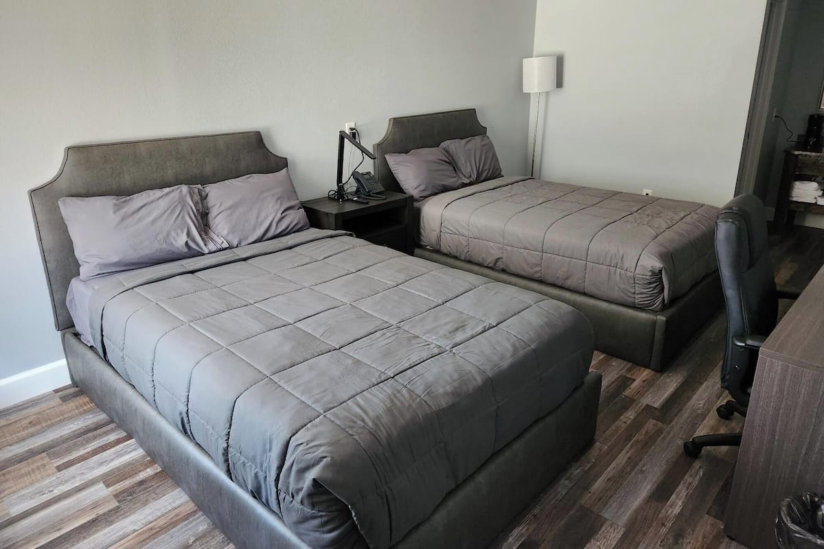 Een hotelkamer met twee bedden, een bureau, een stoel, een lamp en een kleine tafel met een lamp.