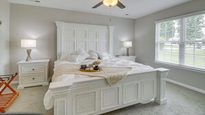 A bedroom with a large bed, two bedside tables with lamps, a ceiling fan, and a window with blinds. - Cozy North Carolina Abode - Minutes from Downtown! (Mount Holly)