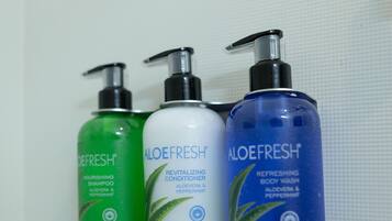 Three bottles of AloeFresh body wash on a white shelf.