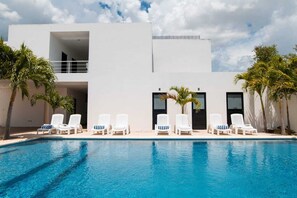 A modern building with a pool, white lounge chairs, and palm trees. - Hotel & Suites Yuca Ville (Mérida)