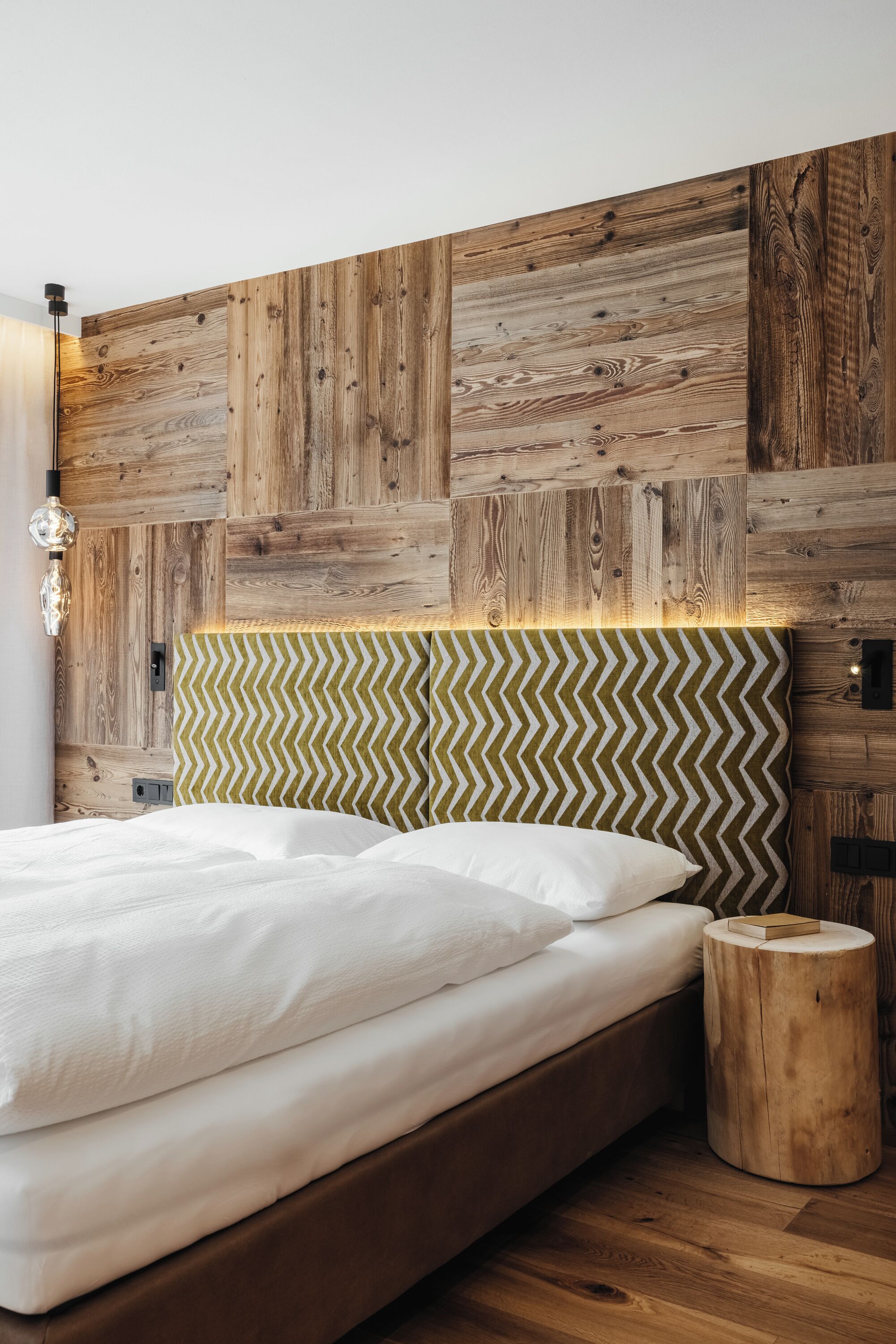 A bedroom with a wooden headboard, a bed with white linens, and a bedside lamp.