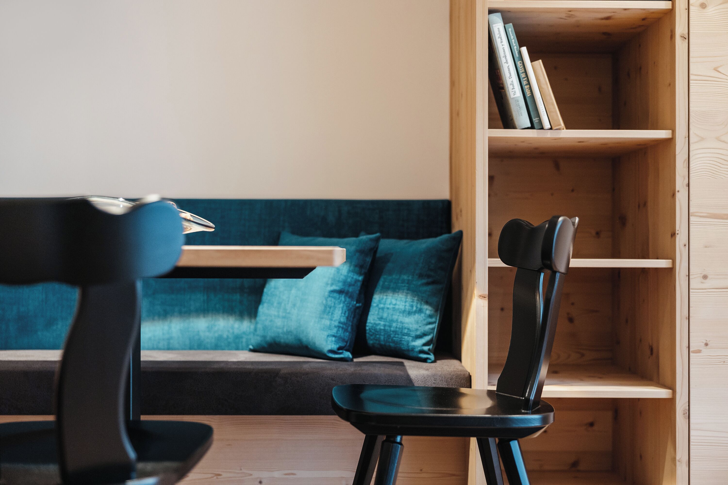 A modern room with a wooden bookshelf, a dark blue sofa, and a black chair.