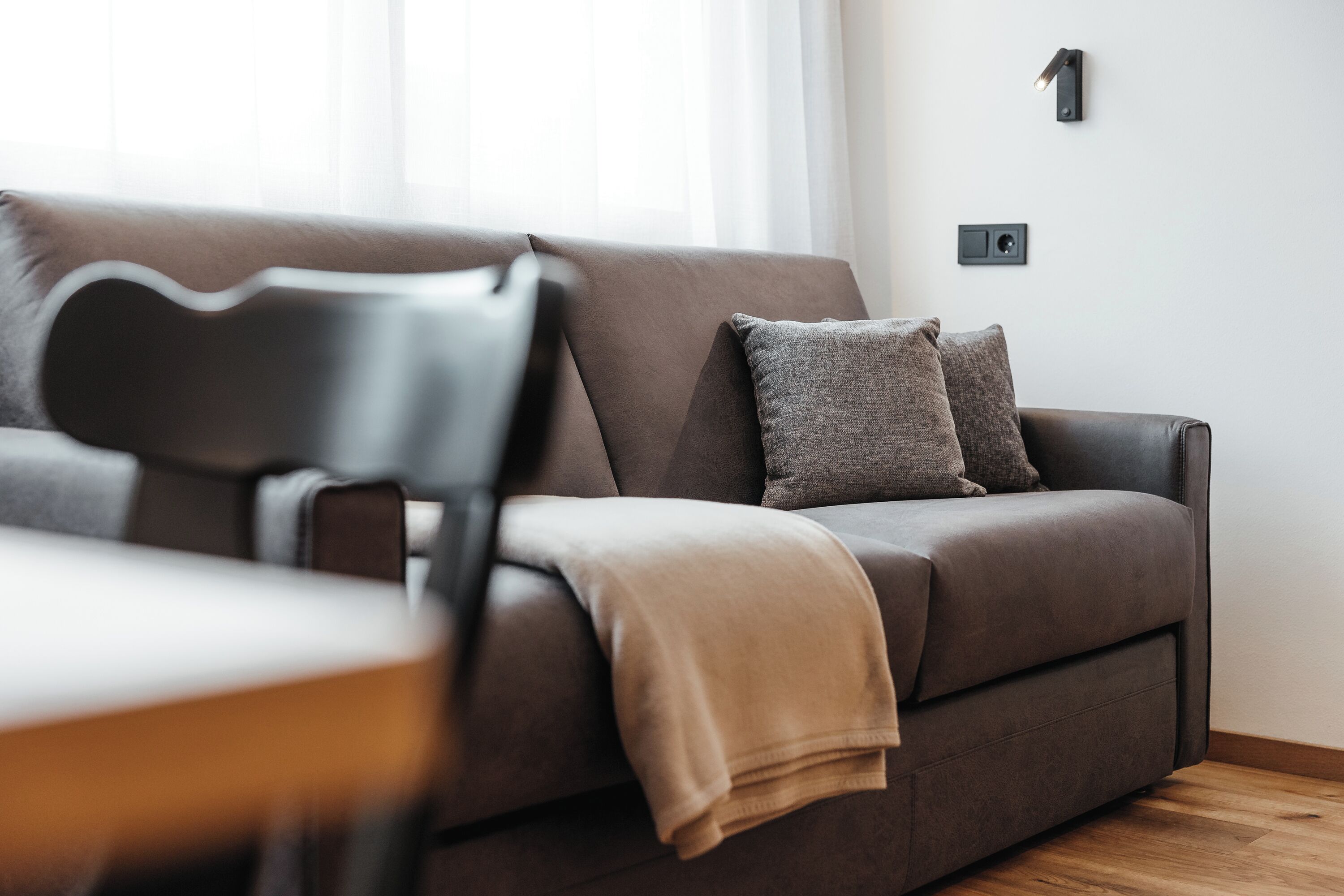 A modern living room with a sofa, a chair, and a blanket.