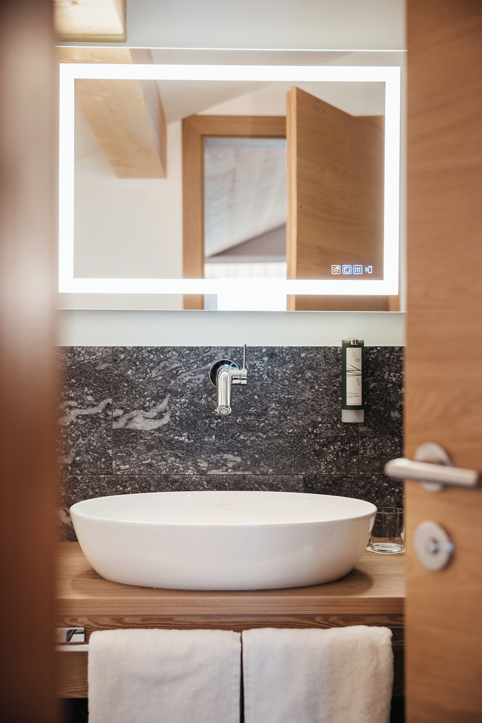 Un baño con un lavamanos grande de color blanco, un espejo encima y un mueble de tocador de madera.
