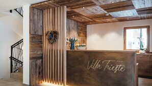 A reception desk with a wooden finish and the name "Villa Frieste" written on it. - Villa Trieste (Corvara in Badia)