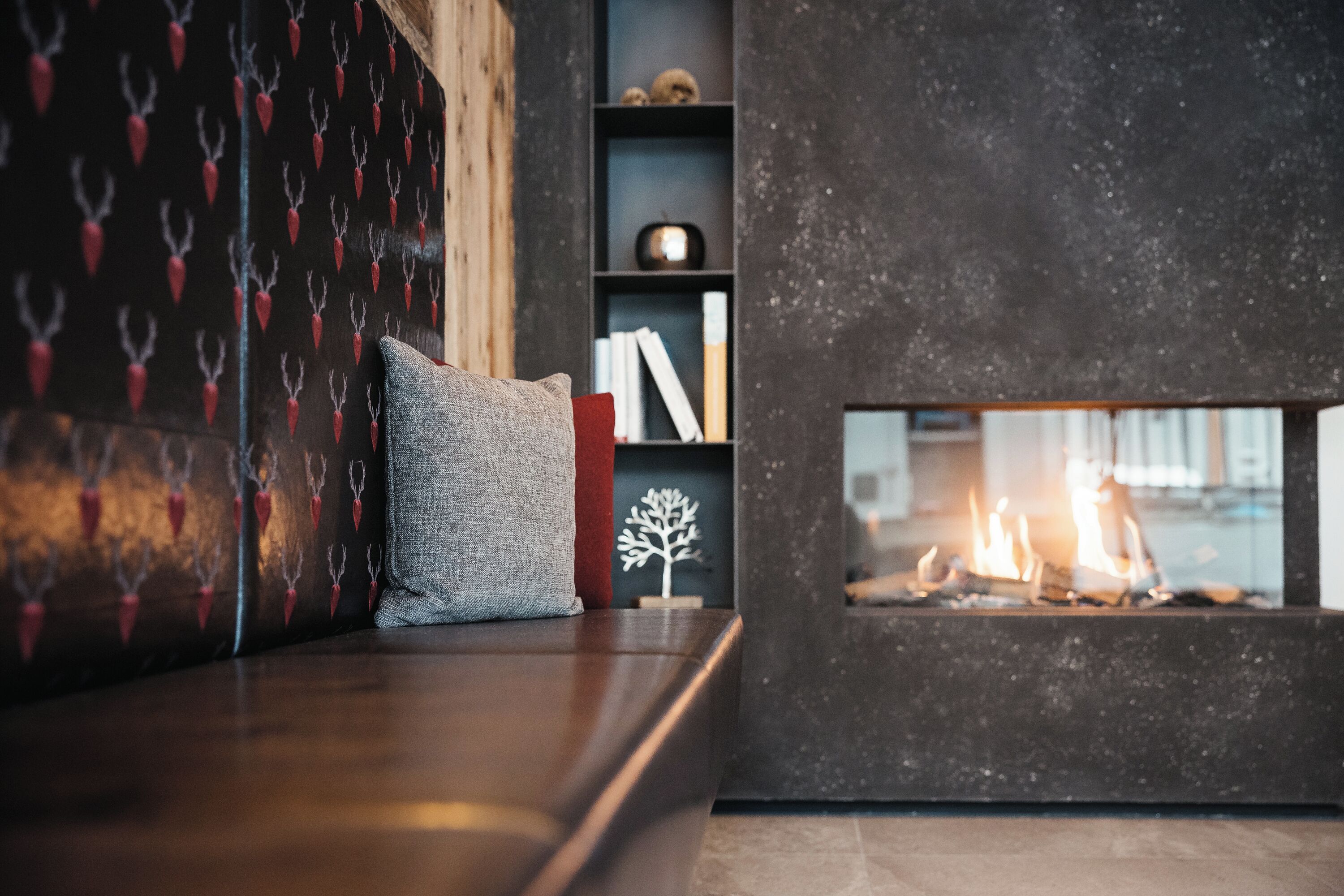 Un salón acogedor con chimenea, estantería y un papel tapiz decorativo.