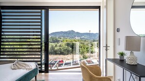 Une chambre avec un lit, une chaise, un bureau et une vue sur un parking et des collines.