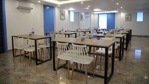 Une salle de conférence dotée de plusieurs tables et chaises, ainsi que de bouteilles d’eau et d’un projecteur.