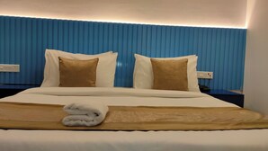 Une chambre d’hôtel avec un lit, deux oreillers, une couverture et une serviette pliée posée sur le lit.
