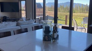 Un intérieur moderne avec une grande table à manger, un canapé et un téléviseur fixé au mur.