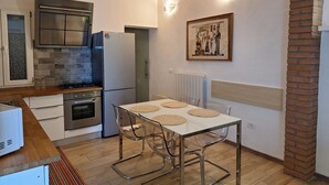 A modern kitchen with a refrigerator, oven, and stove. There is a dining table with chairs and a picture on the wall. - Beautiful renovated house (Mirano)
