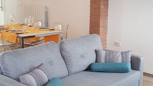 A living room with a grey sofa, a black and white striped rug, a dining table set with glasses, and a framed picture on the wall. - Beautiful renovated house (Mirano)