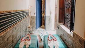 A narrow hallway with two beds, a blue door, and a patterned rug. - Riad Karim (Marrakech)