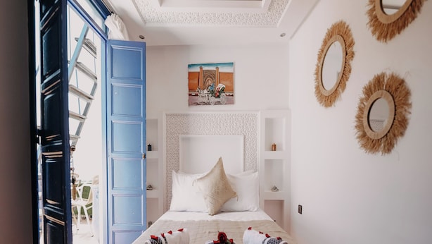 A hotel room with a bed, a painting, and decorative mirrors. - Riad Karim (Marrakech)