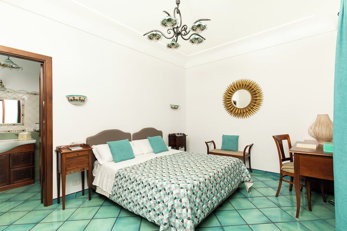 A bedroom with a bed, bedside tables, a desk, and a chair.