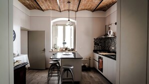 Una cocina moderna con una isla central, taburetes de bar, una lámpara colgante y un salpicadero decorado.