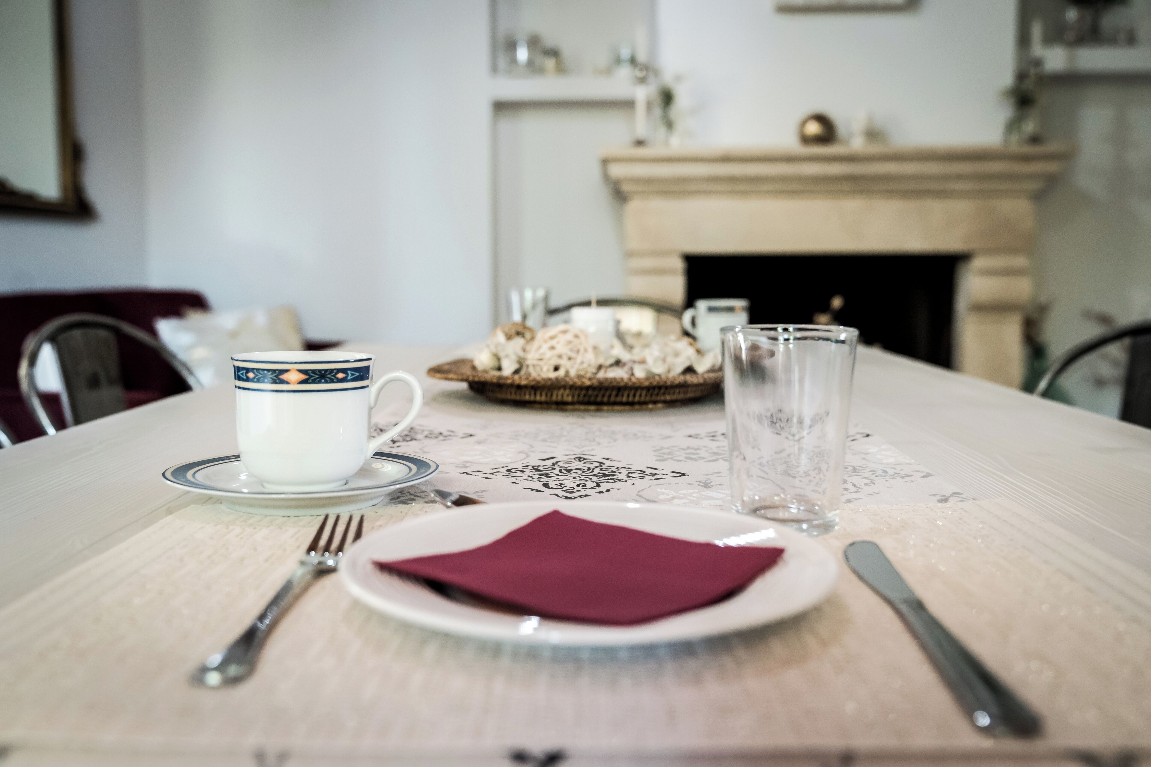 A dining table set with a plate, napkin, fork, and cup.