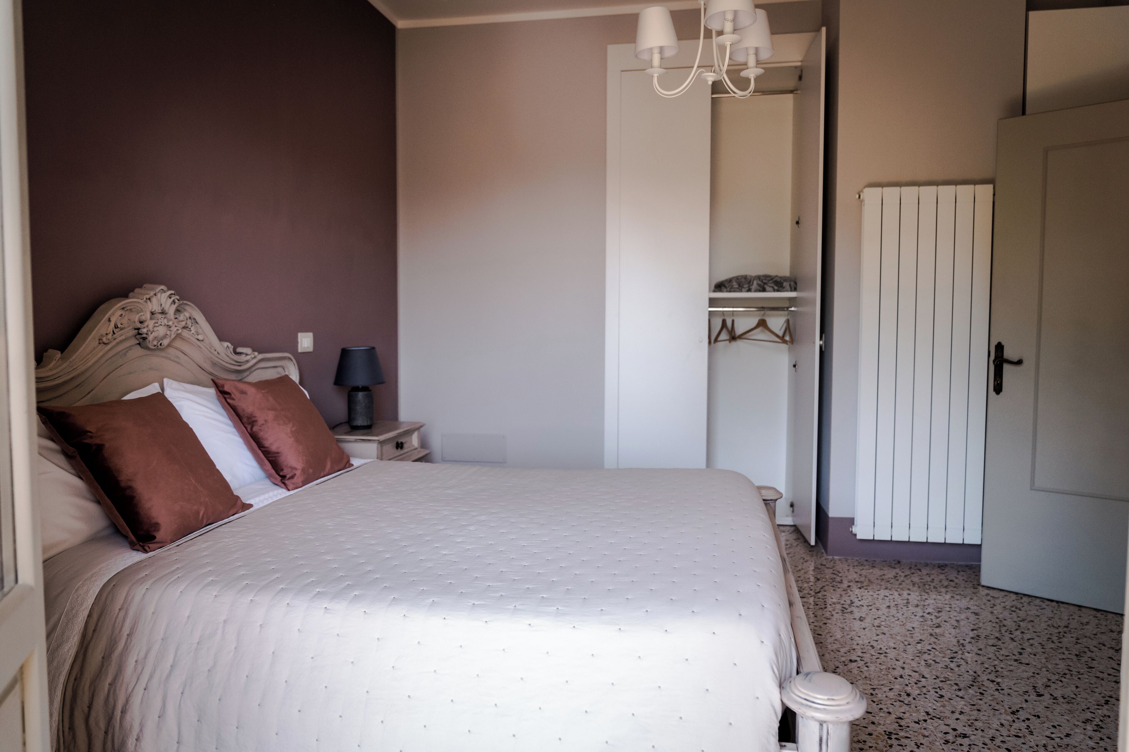 Un dormitorio con una cama grande, una mesita de noche, un armario y una araña.