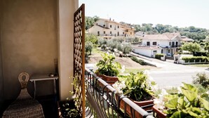 Un balcón con plantas en macetas y vistas a una zona residencial con casas y vegetación.
