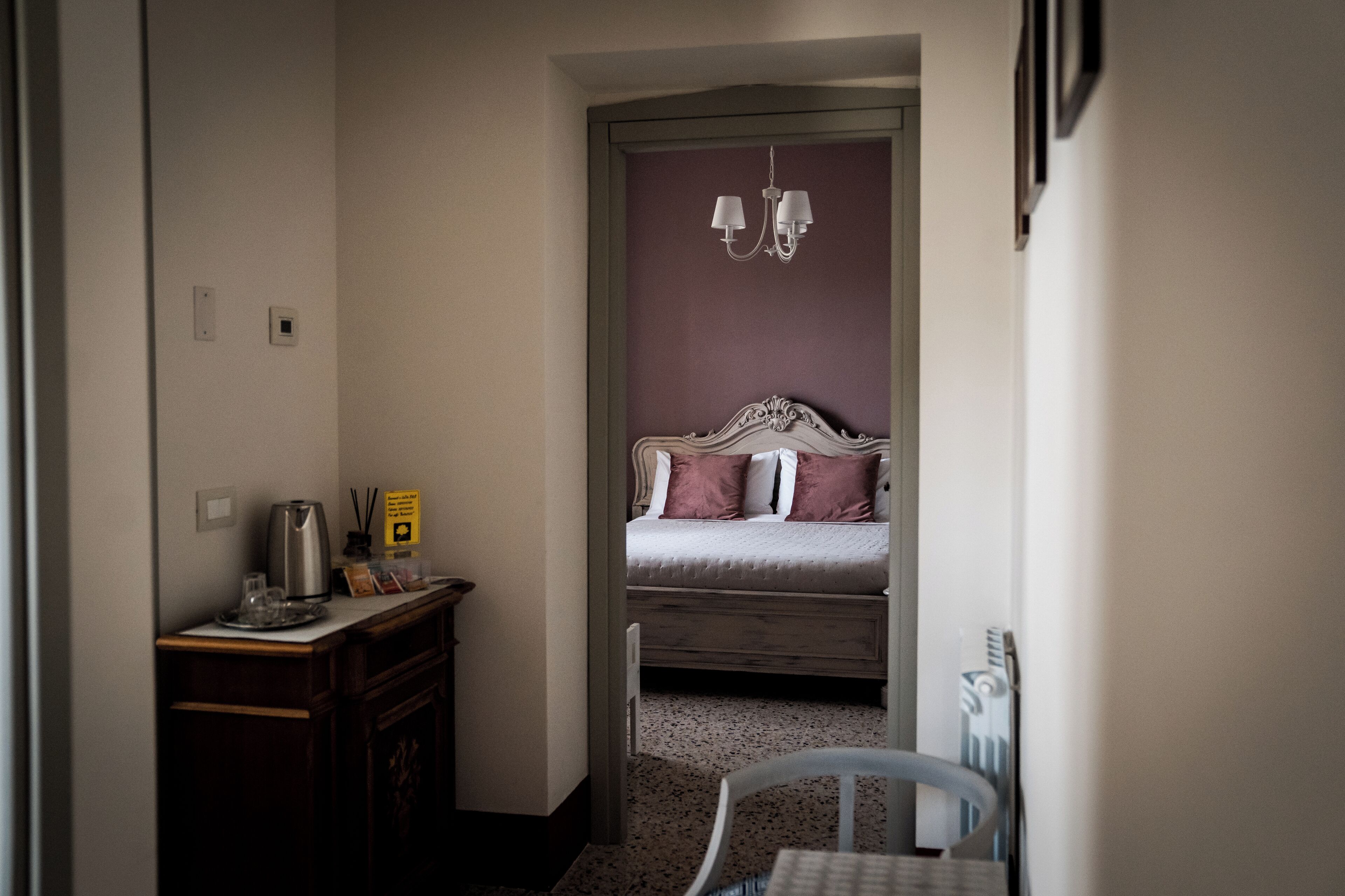 Una habitación de hotel con una cama, un escritorio con hervidor, una silla y una mesita.